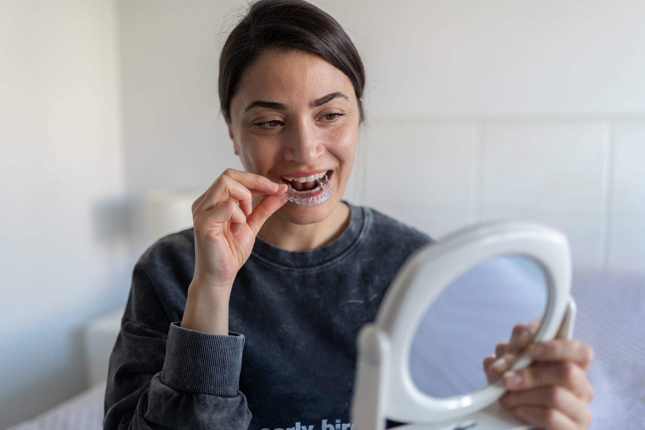 Woman Applying A Transparent Dental Aligner
